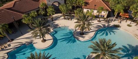 A resort with a large central pool, multiple smaller pools, palm trees, and a well-maintained lawn.