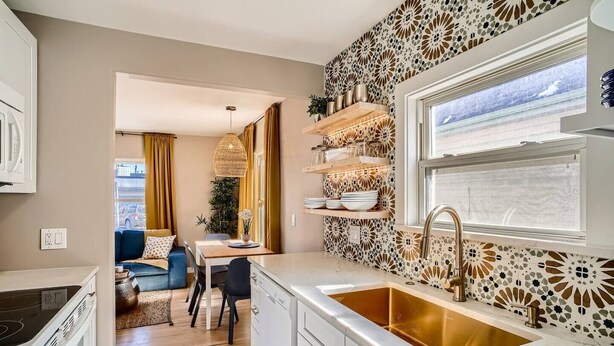 A modern kitchen with a large window, a built-in sink, and a dining area with a blue sofa and a table. - Olde Town Gold-3 bed/2 bath
 (Arvada)
