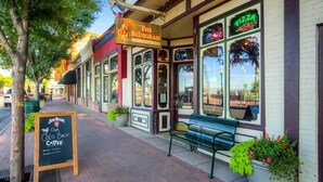 A street view of The Bluegrass Coffee & Bourbon Lounge with outdoor seating and a neon pizza sign. - Olde Town Gold-3 bed/2 bath
 (Arvada)
