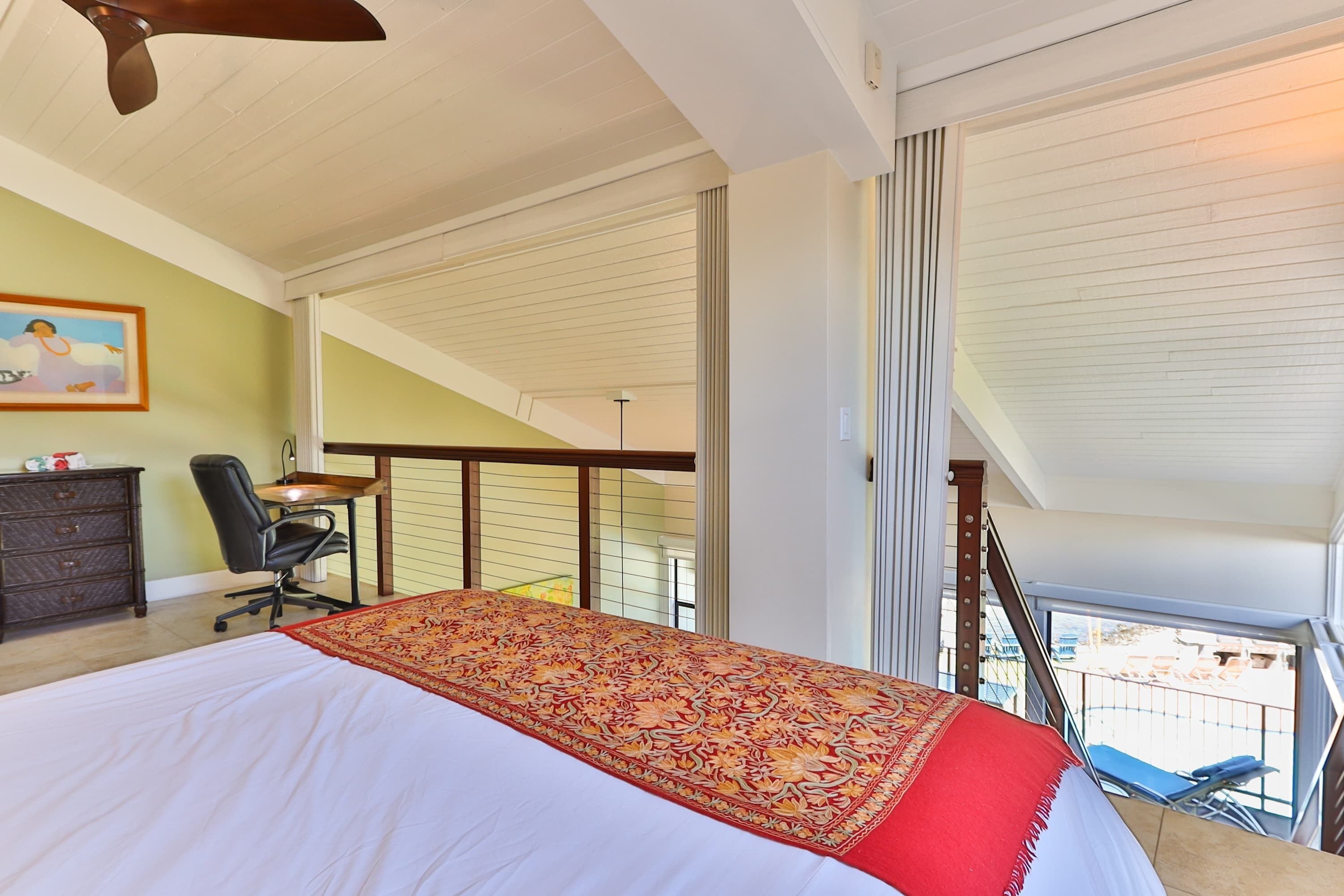 Een slaapkamer met een bed, een bureau, een stoel, een dressoir en een balkon met uitzicht.