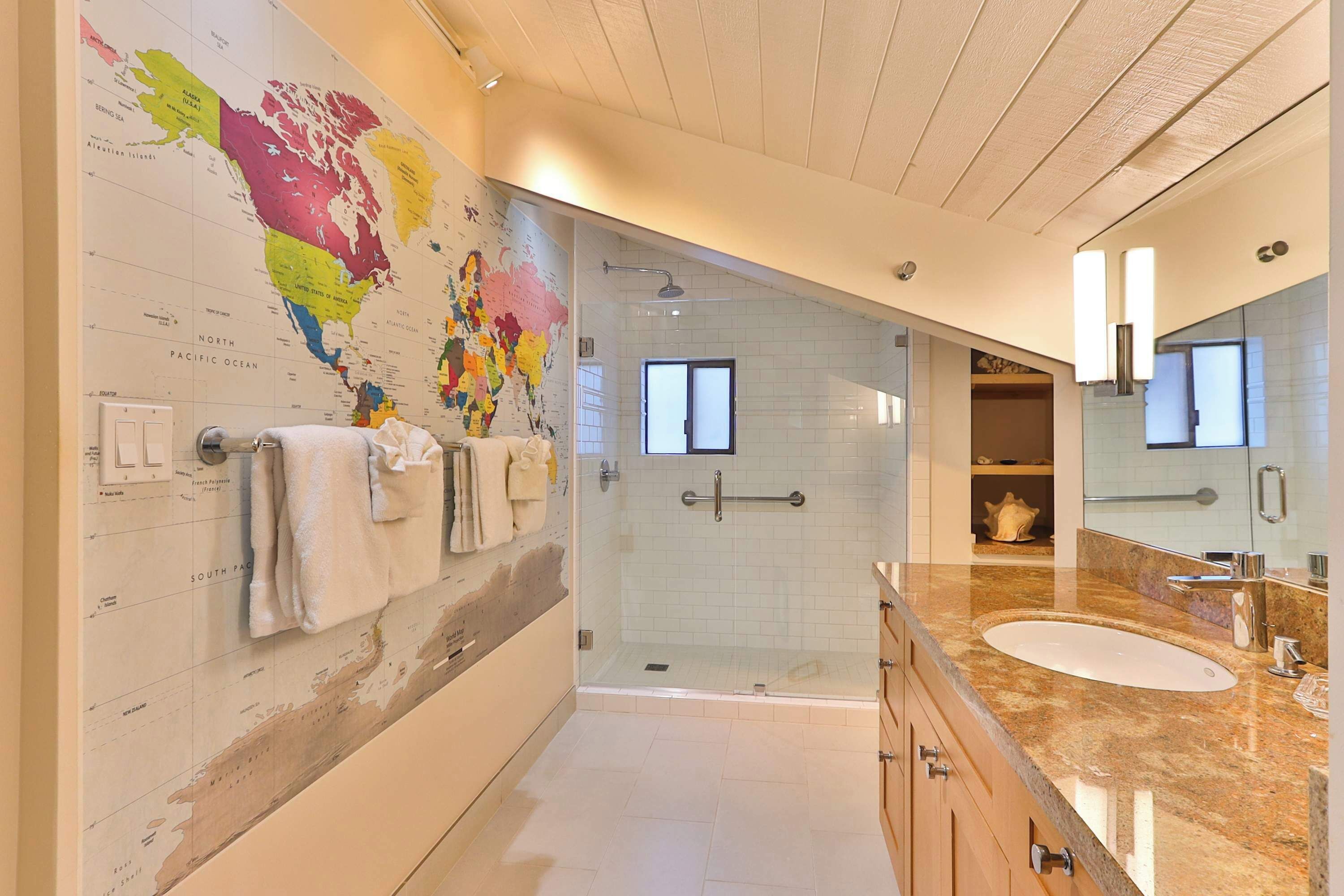 Une salle de bain moderne avec une grande carte murale, une douche en verre, un meuble-lavabo et un grand miroir.