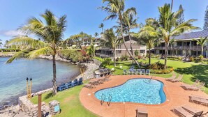 A swimming pool with lounge chairs, palm trees, and a view of the ocean. - Snorkel with sea turtles! Ocean Front & Pool! (Lahaina)