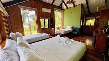 A hotel room with two beds, a wooden ceiling, and large windows.