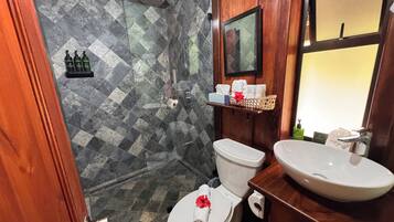 Een badkamer met douche, toilet en wastafel.