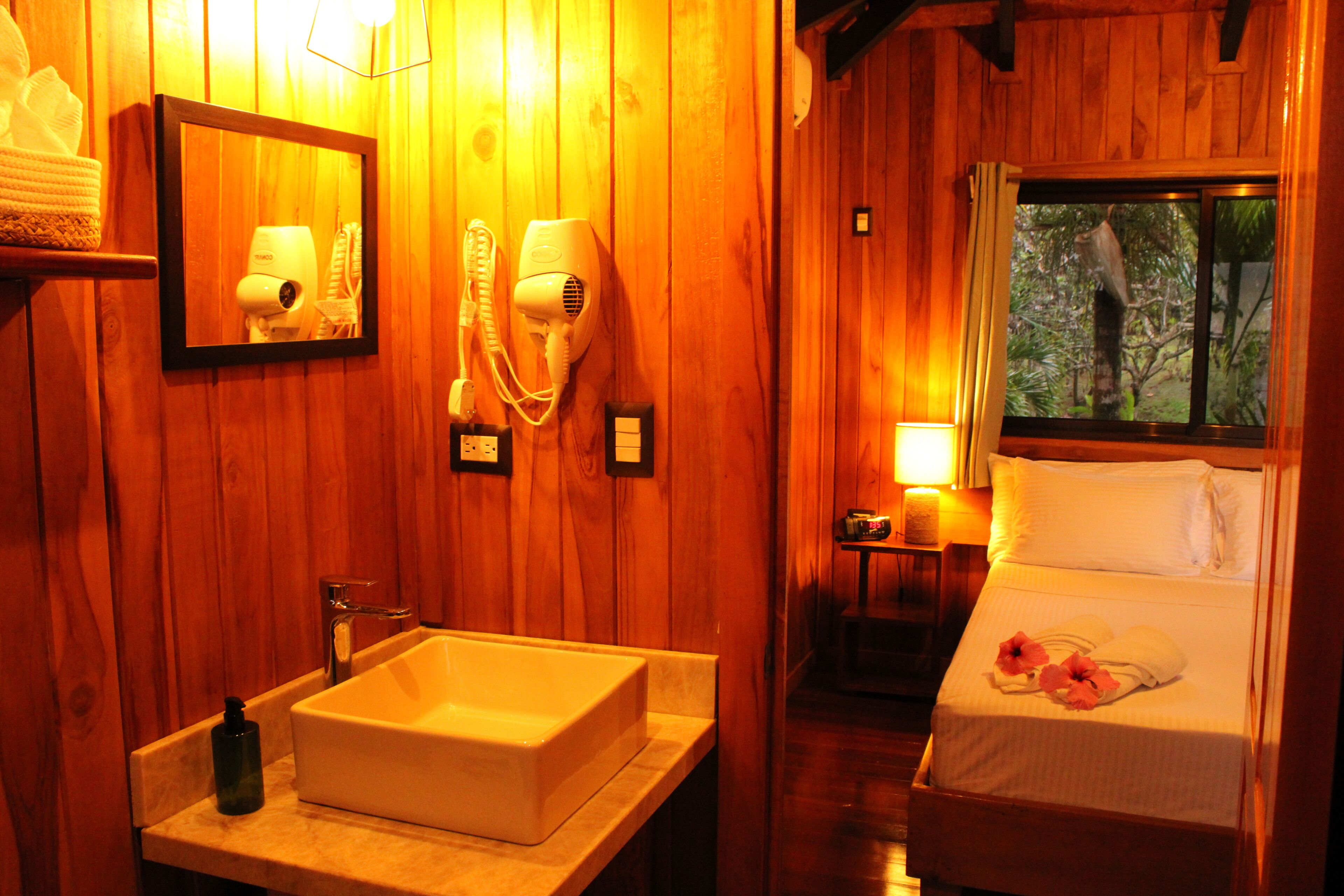 Una habitación de madera con una cama, un lavabo y un espejo.