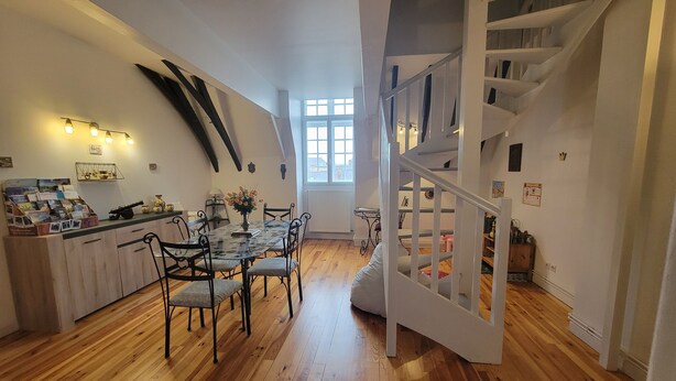 A dining area with a wooden table and chairs, a white staircase, and a window with natural light. - Château des Princes " Fleur de Lys " (Sedan)
