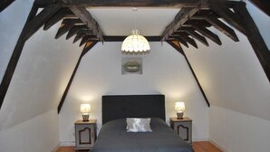 A bedroom with a dark headboard, two bedside tables with lamps, a hanging light fixture, and a small framed picture on the wall. - Château des Princes " Fleur de Lys " (Sedan)