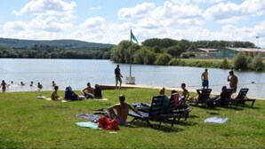 A lakeside area with people relaxing on the grass and in the water. - Château des Princes " Fleur de Lys " (Sedan)
