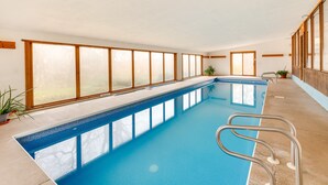 A long indoor swimming pool with clear glass walls, potted plants, and a wooden deck. - Historic Wisconsin Retreat on 26-Acre Property! (Plain)