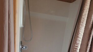 Een douchegedeelte met een handdouche en een afvoer.