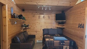Een gezellig houten kamer met een bed, een bank en een televisie.