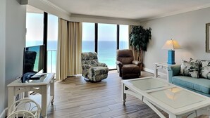 Un salon spacieux doté d’une grande fenêtre donnant sur l’océan, d’un téléviseur à écran plat, d’un canapé, d’une table basse et d’une plante.