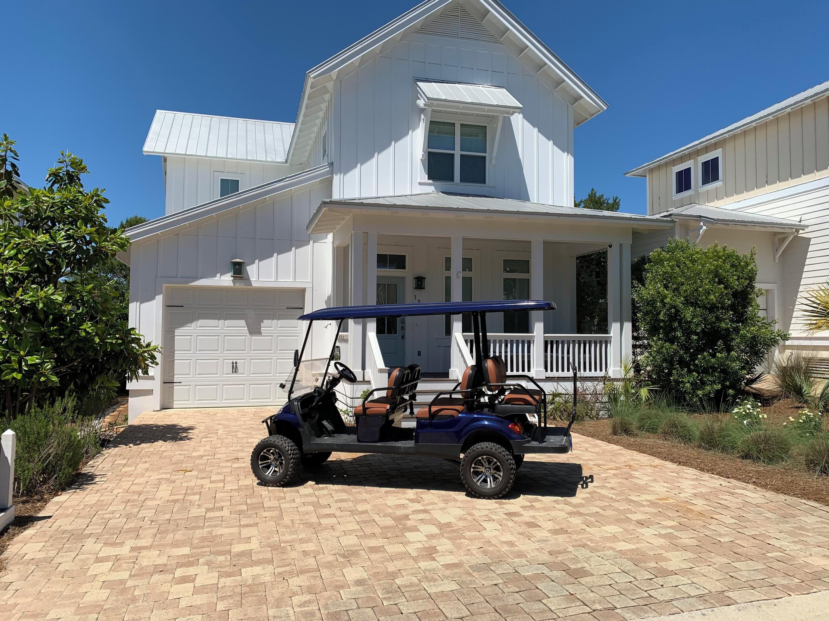 A two-story house with a garage, a covered porch, and a golf cart parked in front.