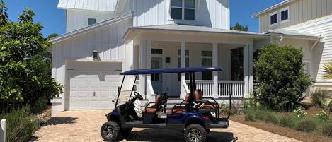 A two-story house with a garage, a covered porch, and a golf cart parked in front.