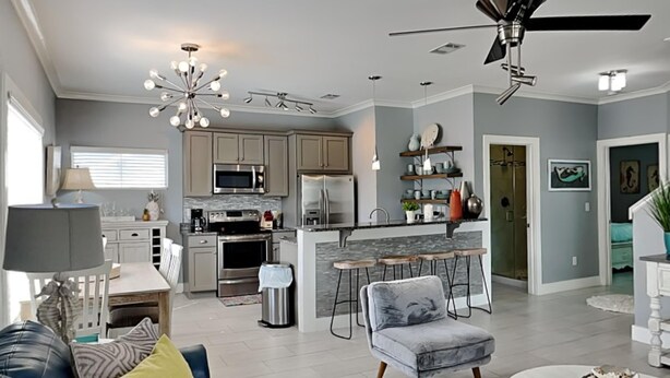A modern kitchen with a central island, bar stools, and a ceiling fan. - Runnin Down A Dream by Southern Vacation Rentals (Miramar Beach)