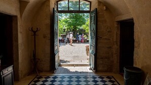 An arched doorway leading to an outdoor area with a checkered floor and a group of people gathered outside.