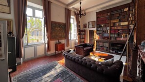 A living room with a large bookshelf, a sofa, a rug, and a chandelier.