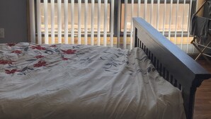 A bedroom with a bed, a wooden bench, and a view through large windows. - 1. Apartment with hot tub and fireplace (Rockaway Beach)