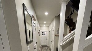 A narrow hallway with wooden flooring, white walls, and a green couch in the corner. - New, 3 Bedroom Home Centrally Located in Moses Lake with Room for all Your Toys! (Moses Lake)