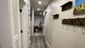 A hallway with wooden flooring, white walls, and a painting on the wall. - New, 3 Bedroom Home Centrally Located in Moses Lake with Room for all Your Toys! (Moses Lake)