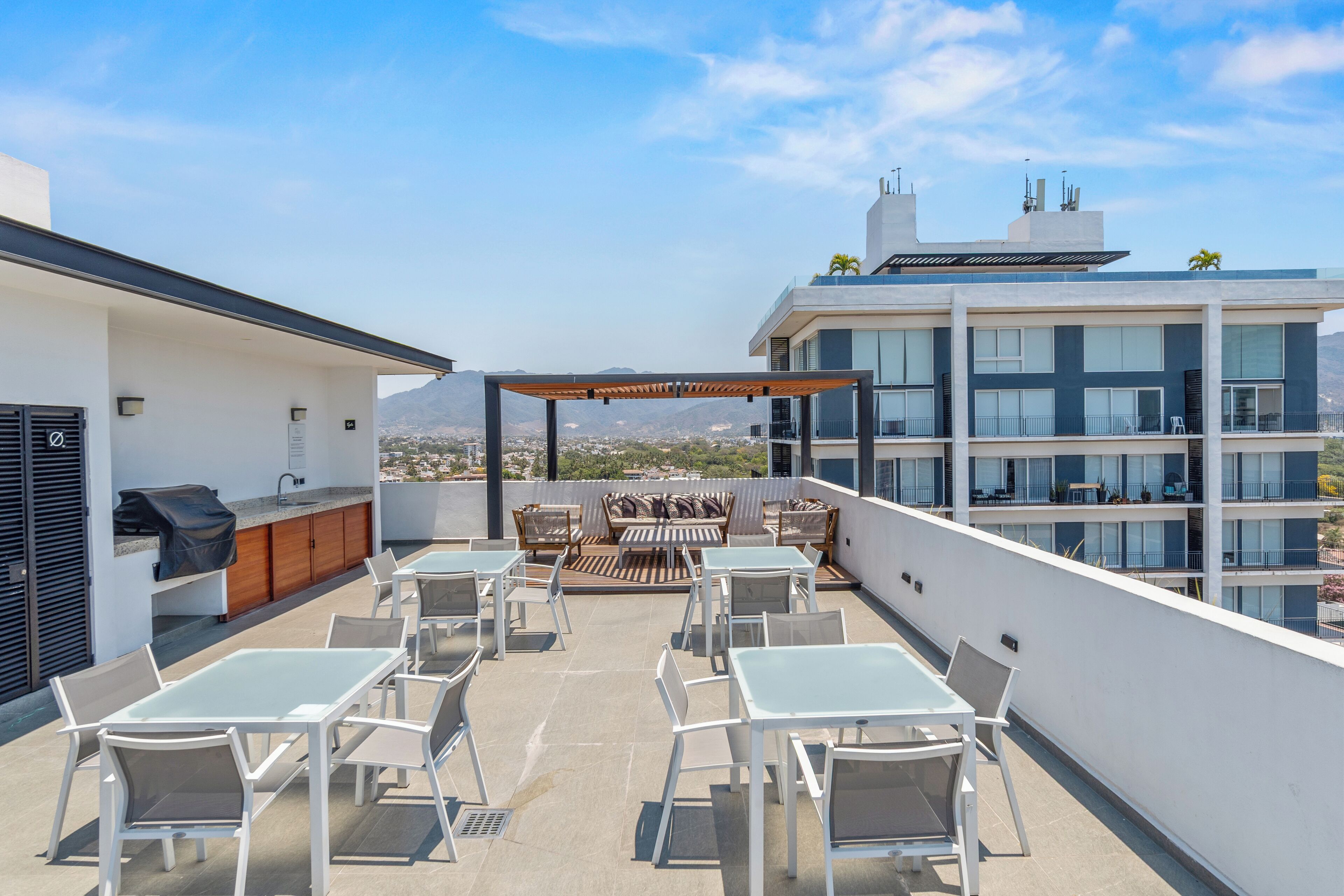 A rooftop terrace with outdoor seating, a grill, and a view of the city.