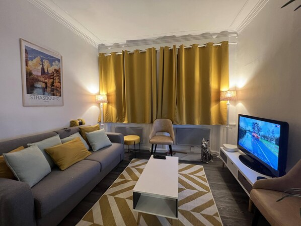 Relax in this stylish living room with a sofa, coffee table, and armchair, perfect for unwinding with a TV and a view.