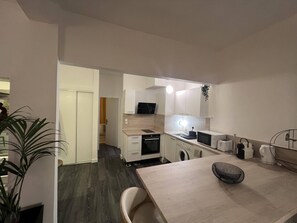 Compact kitchen with a dining area, equipped with a microwave, toaster, and kettle.