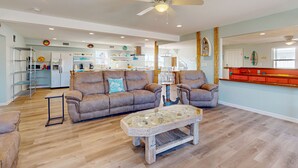 A spacious living room with a wooden coffee table, two leather sofas, and a ceiling fan. - Wet Bar, Outdoor Games, Gulf Views, Pet Friendly (Port Aransas)