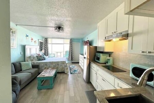 A compact living space with a kitchenette, a sofa, a coffee table, and a dining area.