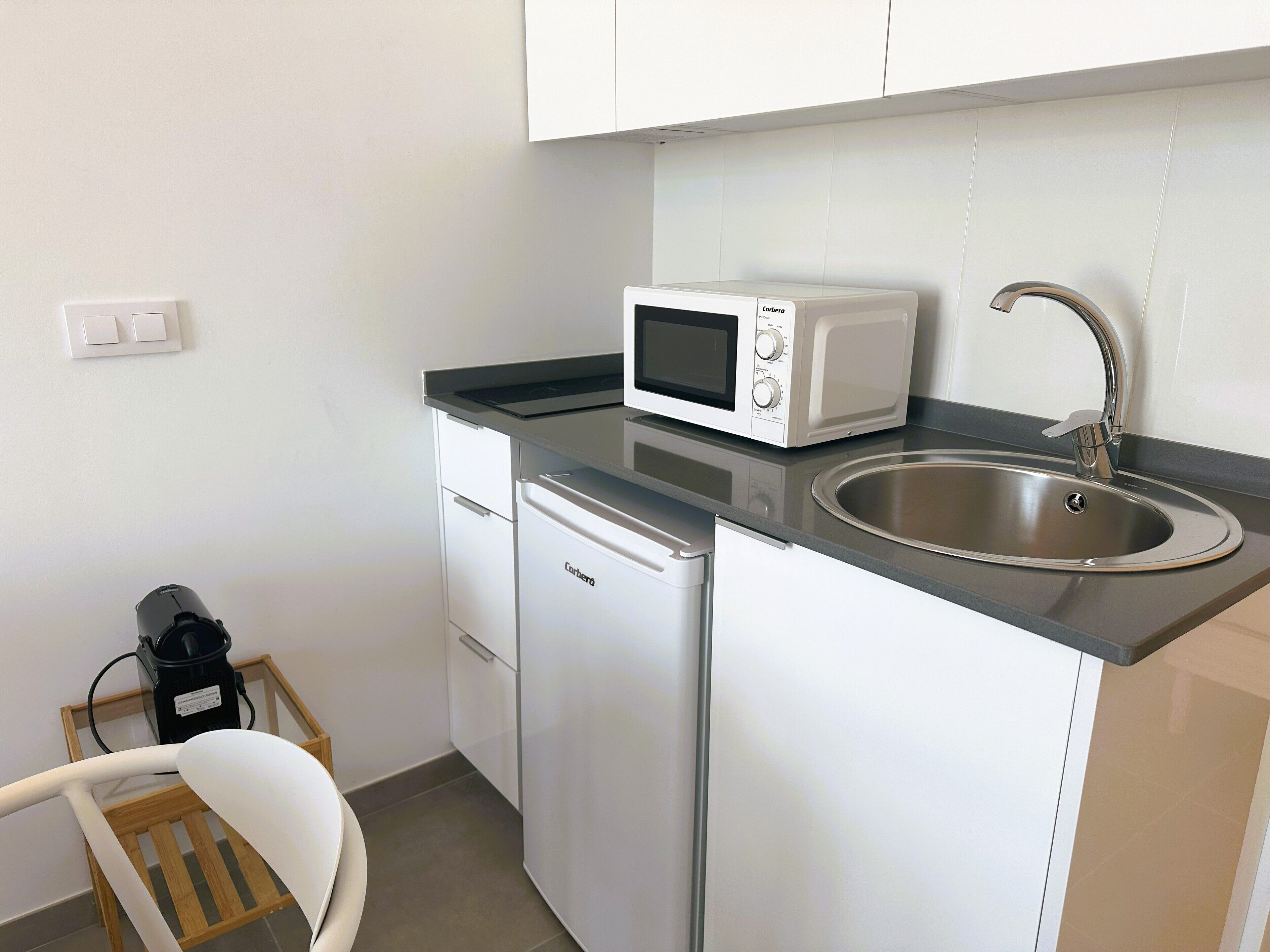 A compact kitchenette with a microwave, sink, and dishwasher.