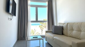 Una sala de estar moderna con un sofá, un televisor de pantalla plana en la pared y una ventana con cortinas.
