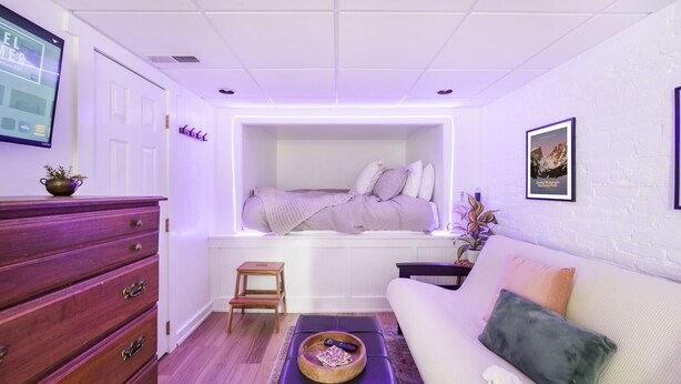 A compact room with a built-in bed, a wooden dresser, a small stool, and a sofa. - Cozy Guest Suite in West Highlands (Denver)