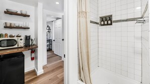 A modern kitchen with a microwave, coffee maker, and shelves with dishes. - Cozy Guest Suite in West Highlands (Denver)