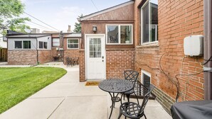 A residential backyard with a patio, a door, and a brick wall. - Cozy Guest Suite in West Highlands (Denver)