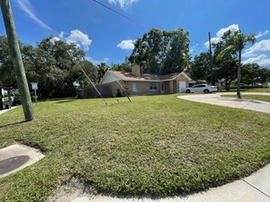 Un césped residencial con una casa al fondo.