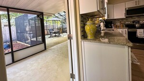 A kitchen with white cabinets, a yellow vase, and a sliding glass door leading to an outdoor patio.