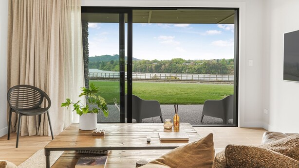 A modern living room with a large sliding glass door leading to a scenic outdoor view.