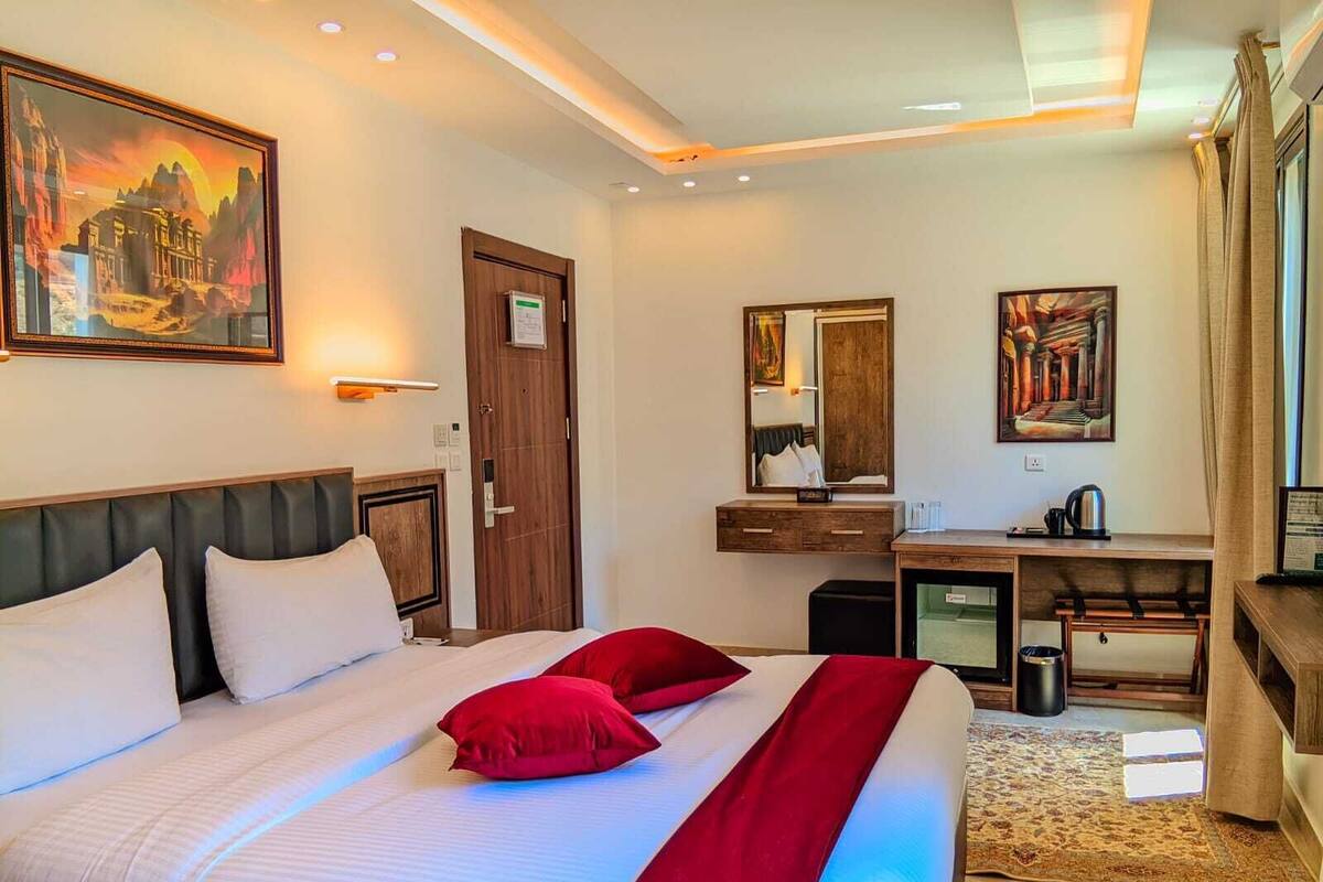 Habitación de hotel con una cama grande, un escritorio, un espejo y un cuadro en la pared.
