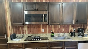 A kitchen with dark wooden cabinets, a stainless steel microwave, a gas stove, a sink, and a coffee maker. - 2. Apartment with Lake View (Rockaway Beach)