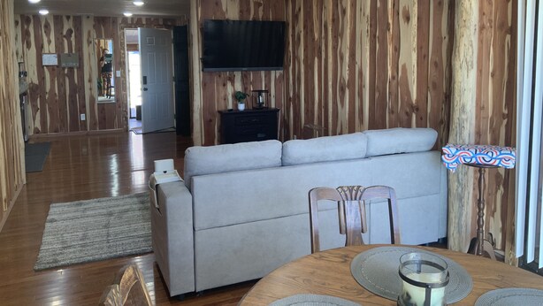 A modern living room with a sofa, dining table, and chairs. A flat-screen TV is mounted on the wall. - 2. Apartment with Lake View (Rockaway Beach)
