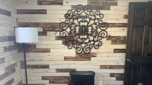 A room with a wooden wall panel design, a decorative metal piece, a vintage stove, a floor lamp, and a door. - 2. Apartment with Lake View (Rockaway Beach)