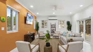 Ein modernes Wohnzimmer mit einer Couch, Sesseln, einem Couchtisch und einem Bücherregal.