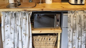 Een kleine keuken met houten wanden, een magnetron, een broodrooster en een koffiezetapparaat.
