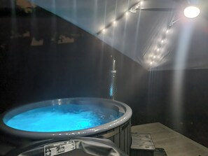 Un bain à remous doté d’une étiquette d’avertissement bien visible, situé dans un espace intérieur sombre éclairé par un luminaire au plafond.