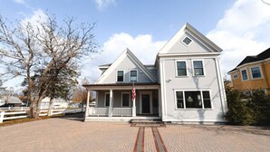 A two-story house with a front porch and a flagpole.