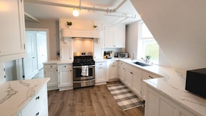 Une cuisine moderne avec des meubles blancs, une cuisinière en acier inoxydable et un tapis à carreaux.