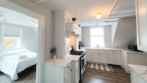 Une cuisine moderne et compacte, avec des meubles blancs, un îlot central et un four encastré.