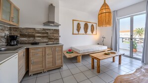A modern kitchen with a stone backsplash, wooden cabinets, and a dining area with a bench and table. - Kalimera apartment 5 ,Near beach and all amenities (Adelianos Kampos)