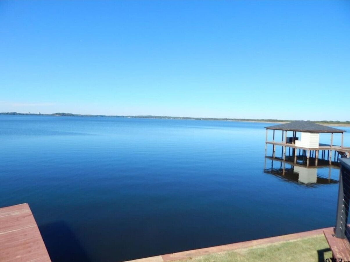 Un lac paisible avec un quai et un petit bâtiment.