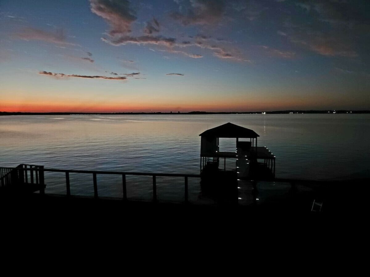 Un muelle con un pequeño refugio al final, con vista a aguas tranquilas durante el atardecer.